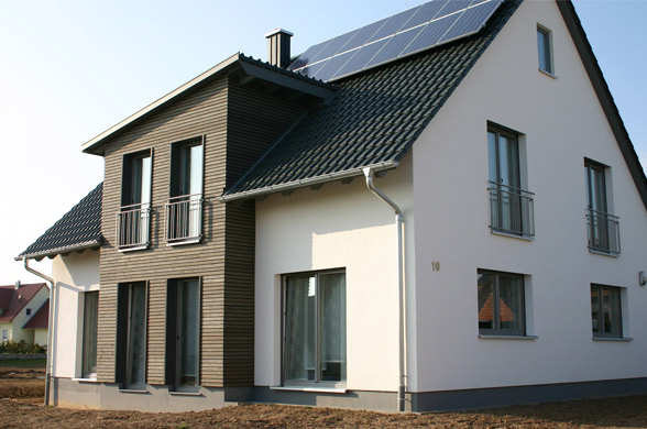 Neubau eines Einfamilienhauses mit modernem Erker in Holzverkleidung und Schleppgaube und Photovoltaik.