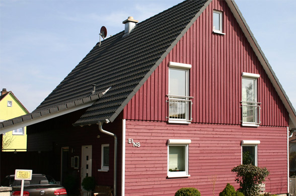 Modernes Holzhaus mit Satteldach und angebautem Überdach.