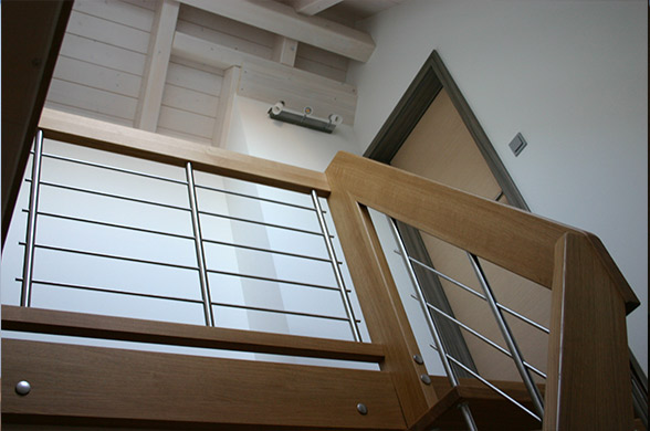 Innenausbau mit Holztreppe und Holz-Edelstahl Handlauf und einer Holzdecke.
